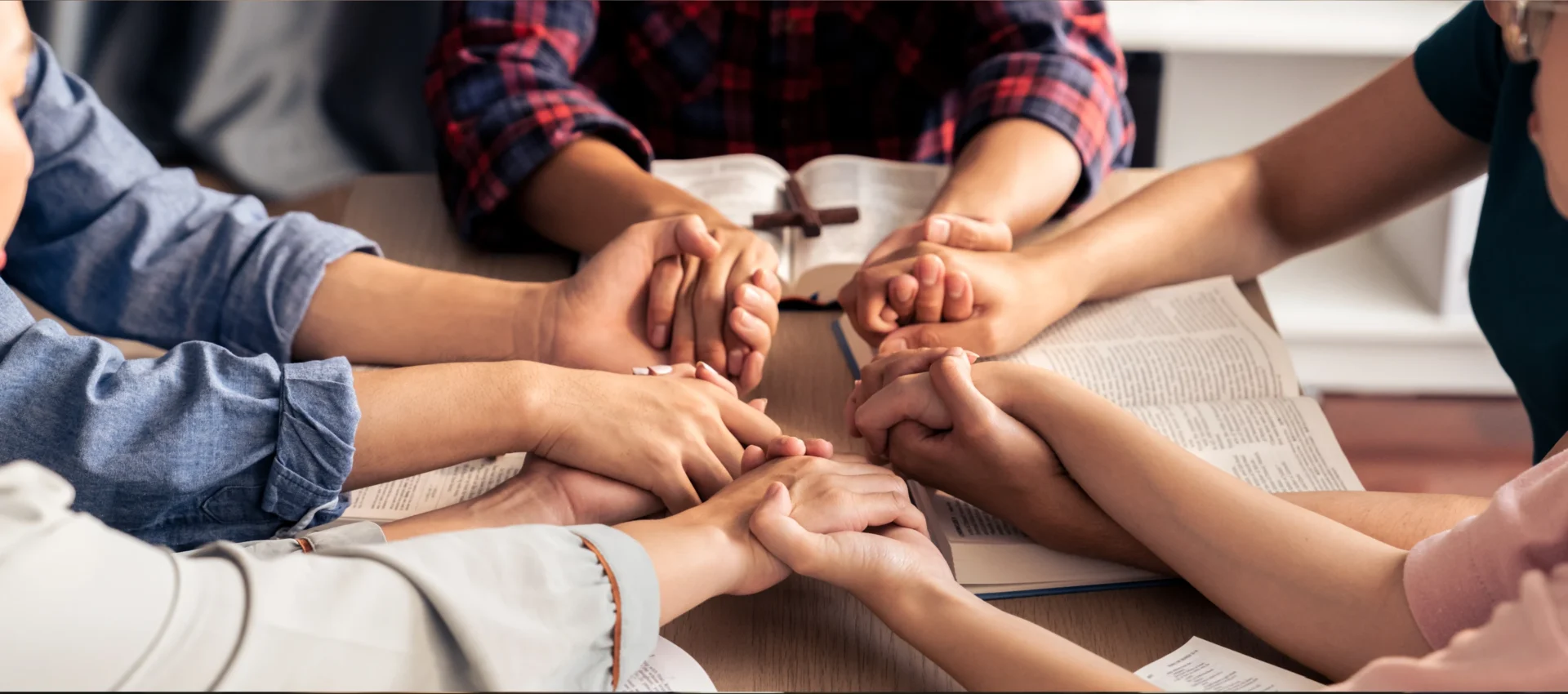A group of people holding hands in front of an open bible.